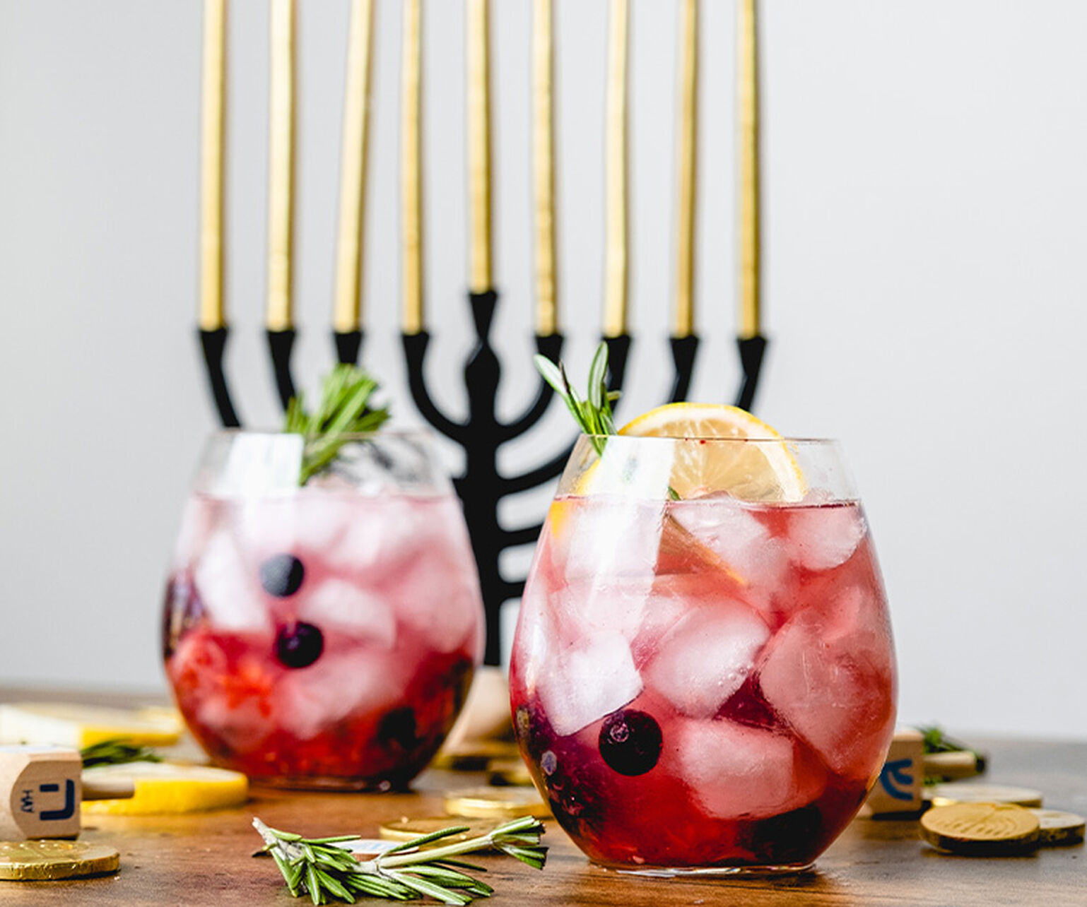 A berry vodka cocktail is seen in front of a Menorah and Dreidel 